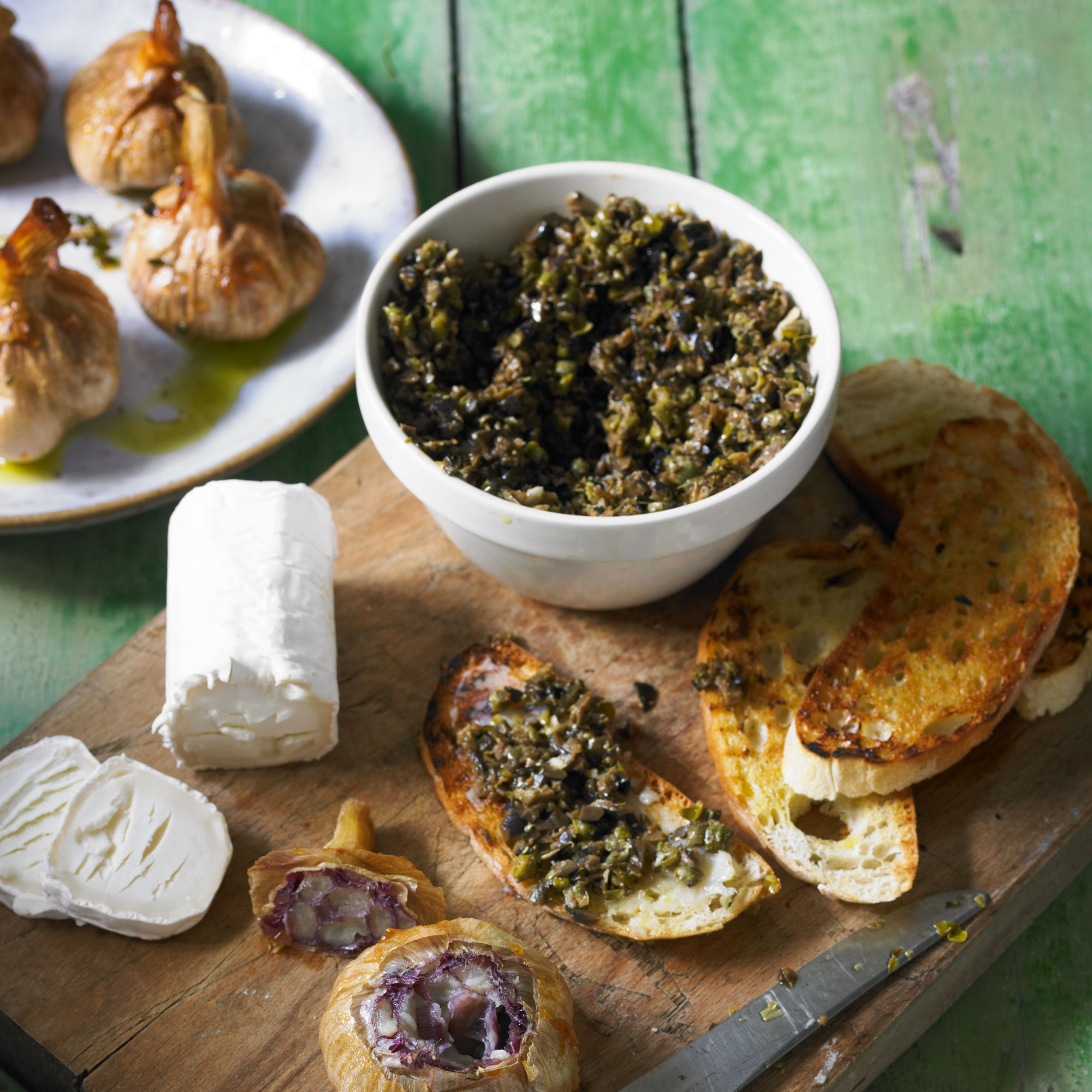 Braised new seasons garlic with tapenade toasts and fresh goats' cheese recipe